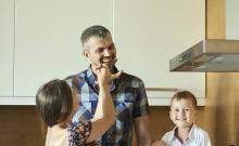 Two kids feeding their father dinner