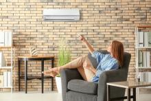 A woman sitting on a chair and turning on her heat pump