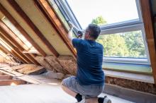 man caulking a window in an attic