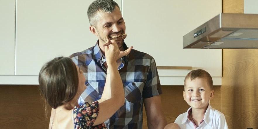 Two kids feeding their father dinner