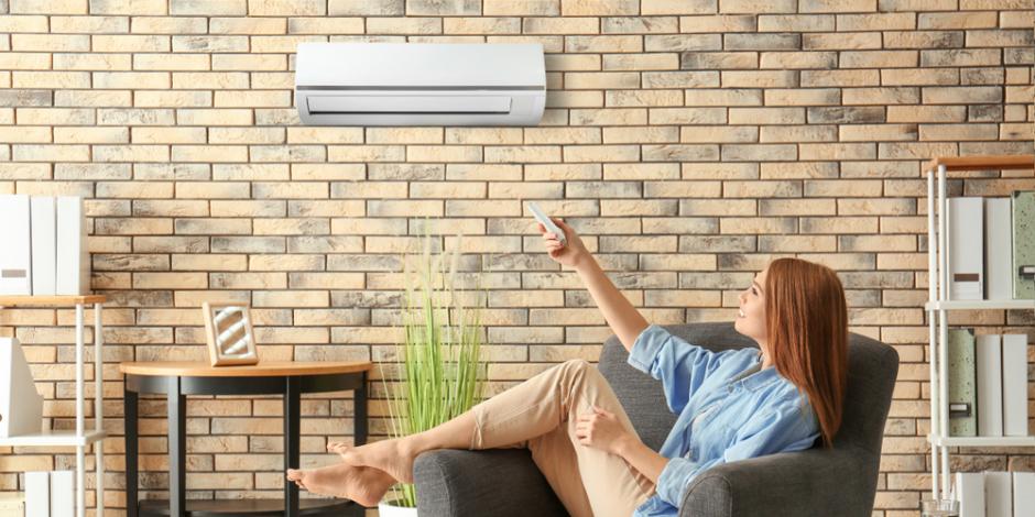 A woman sitting on a chair and turning on her heat pump