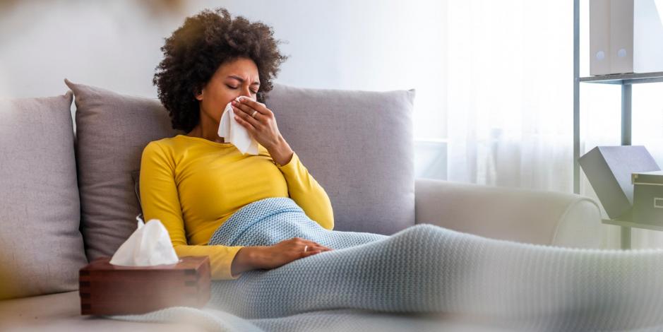 Woman inside blowing nose due to poor indoor air quality