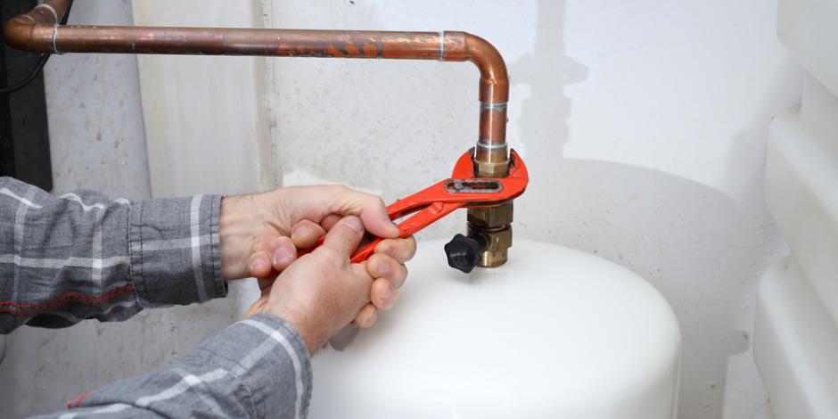 worker with tool in hand is repairing a boiler